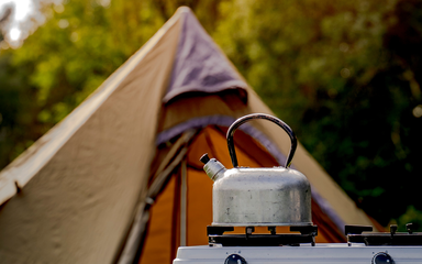 A kettle on a hob in front of a tent
