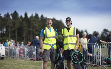 Two men dressed in high vis volunteering to pick up litter at Forest Live concert