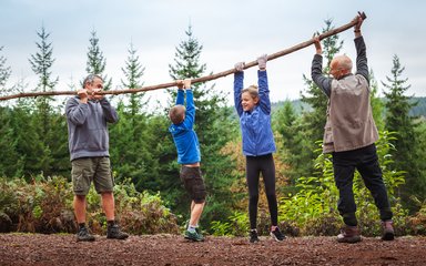 Family lifting branch and playing in front of forest landscape